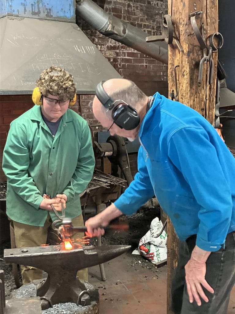 youth adult forging at anvil